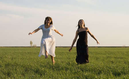 Two beautiful girls running on the green fieldの写真素材