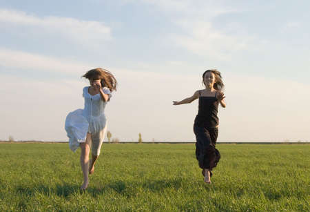 Two beautiful girls running on the green fieldの写真素材