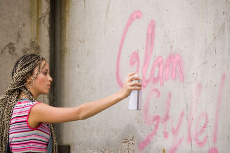 girl painting on the gray and dirty wallの写真素材