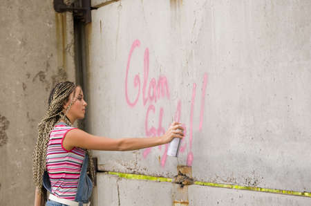 girl painting on the gray and dirty wallの写真素材