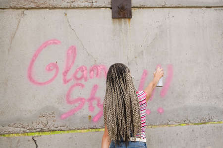 girl painting on the gray and dirty wallの写真素材