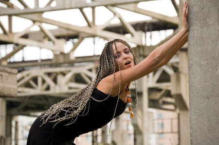 fashionable girl in black dress on the dirty industrial place and constructions backgroundの写真素材