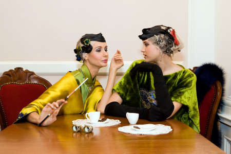 two beauty talking girls sit sitting at the wood tableの写真素材