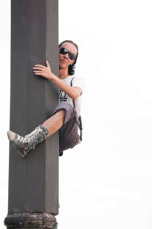 boy in casual wear clamber up to column on white backgroundの写真素材