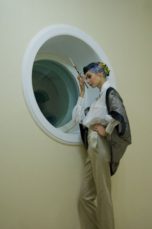 beauty girl with cigarette thinking beside white circle windowの写真素材