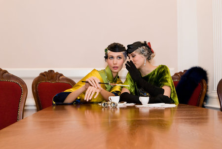 two beauty talking girls sitting at the wood tableの写真素材