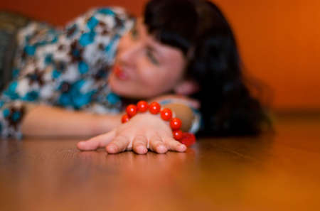 hand of girl with orange bracelet on the parquet floorの写真素材