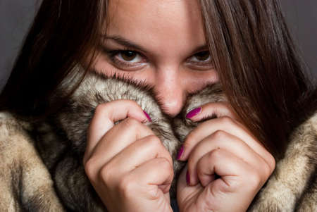 beauty girl with brown hair hiding in fur coatの写真素材