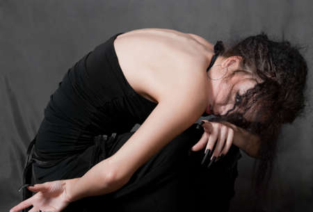 beauty young witch with black nails siting on gray backgroundの写真素材