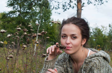 beauty girl sit on meadow near burdock on the trees backgroundの写真素材