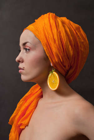 beauty girl with orange headscarf and fruit earring on gray backgroundの写真素材