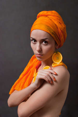 beauty girl with orange headscarf and fruit earring on gray backgroundの写真素材