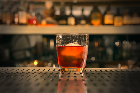 Glass of whiskey with ice on the bar counter. Blurred backgroundの写真素材
