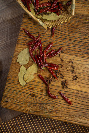 Dried red chili peppers and bay leaf on a wooden cutting boardの写真素材