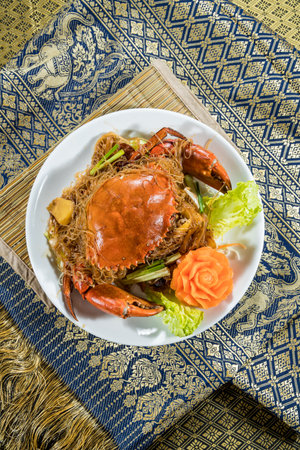 Whole cooked crab served on glass noodles with lettuce, green onions, and carved carrot garnish.の写真素材