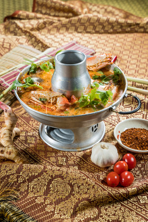 Thai-style Tom Yum hot pot with shrimp, mushrooms, and herbs, styled with cultural props and ingredients.の写真素材