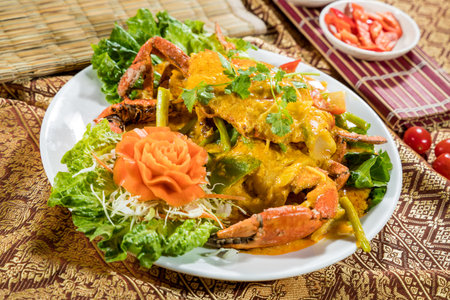 Thai-style crab in yellow curry sauce with bell pepper, onion, and cilantro, served with cabbage and carved carrot flower.の写真素材
