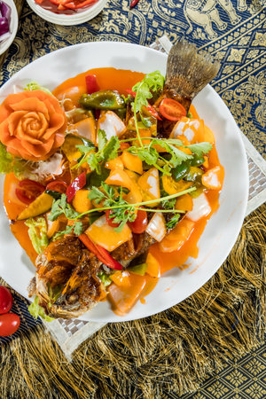 Thai-style fried fish topped with sweet and sour sauce, bell pepper, onion, pineapple, and cilantro.の写真素材