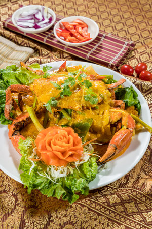 Thai-style crab in yellow curry sauce with cilantro, carrot, and shredded vegetables on white plate.の写真素材