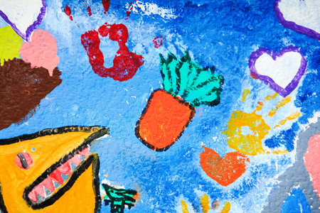 A whimsical mural with hearts, handprints, a carrot, and a yellow creature with sharp teeth on a...
