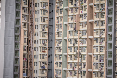 A high rise building with identical balconies and windows, many with air conditioners and drying clothes, showing city living conditions.の写真素材