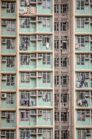 A high rise building showing contrast between newer green speckled sides and a weathered central section with laundry and air units.の写真素材
