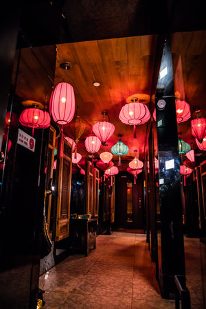 A hallway decorated with multiple red and turquoise lanterns creating a warm and stylish ambiance.の写真素材