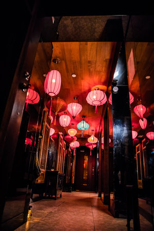 A hallway decorated with multiple red and turquoise lanterns creating a warm and stylish ambiance.の写真素材