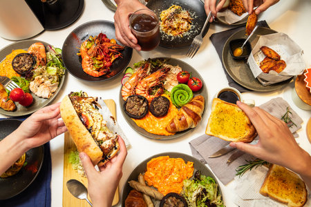 A table filled with various brunch dishes including croissants, eggs, grilled vegetables, shrimp, and drinks.の写真素材