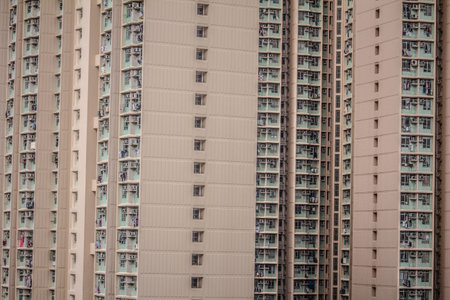 A densely packed high-rise building with grid-like balconies, laundry, and air conditioning units,...