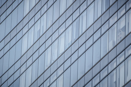 A modern glass building with diagonal panel arrangement, reflecting surroundings and revealing...