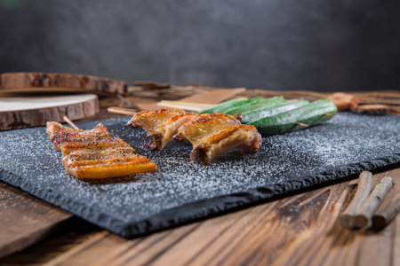 Grilled chicken wings skewers seasoned with spices, served on a black slate with garnish.