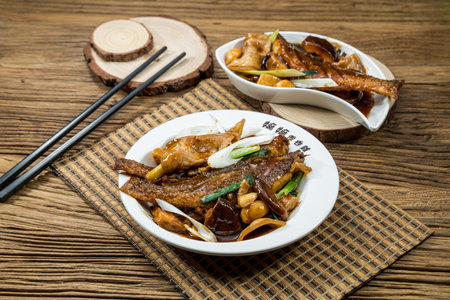 Two plates of braised fish fillets cooked with mushrooms, green onions, and garlic in rich brown...