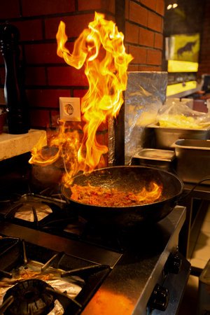 Flaming food in a frying pan in a restaurant kitchen.の写真素材