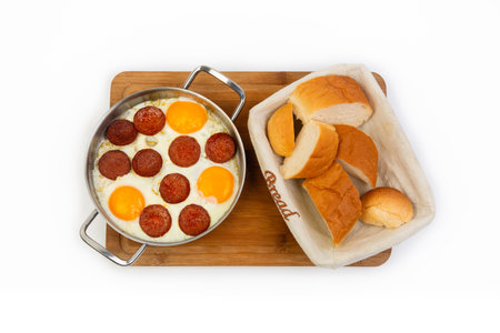 Fried eggs with sausages and bread on a wooden boardの素材