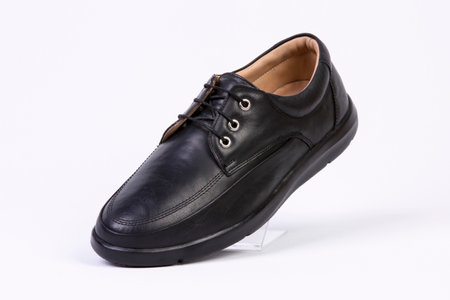 Men's black leather shoes on a white background, studio shot.の素材