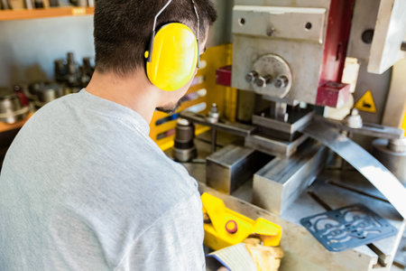 Portrait of a young man working on a machine in a factoryの素材