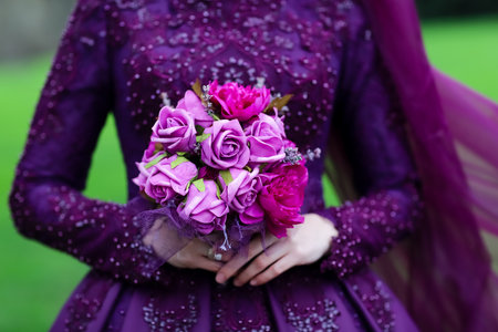 Wedding bouquet in the hands of the bride in a purple dressの素材
