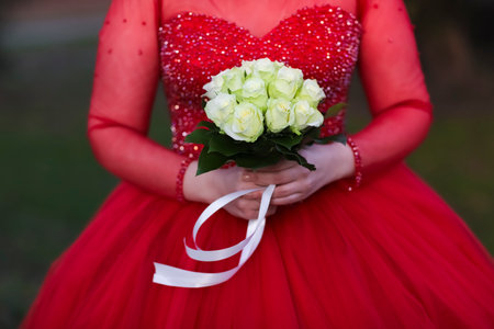 Wedding bouquet in the hands of the bride in a red dressの素材