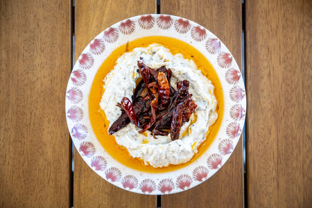 Cottage cheese with dried chillies in white plate on wooden tableの写真素材