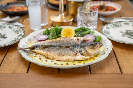 Fried fish with lemon and arugula on a plate.の写真素材