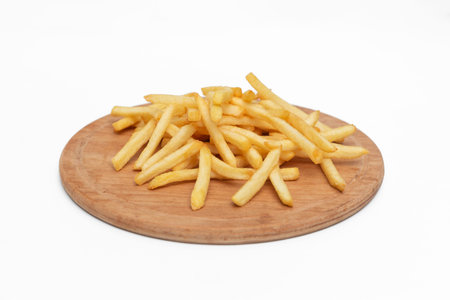 Golden French fries potatoes on a wooden plate isolated on white background.
