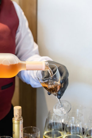 Waiter pouring white wine from bottle into glass, close-upの写真素材