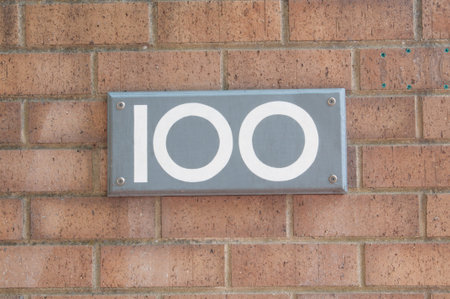 Number 100 on wooden plaque mounted to a brick wallの写真素材