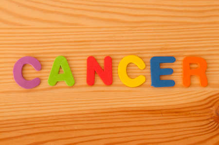 Foam letters spelling out the word cancer on a wooden backgroundの写真素材
