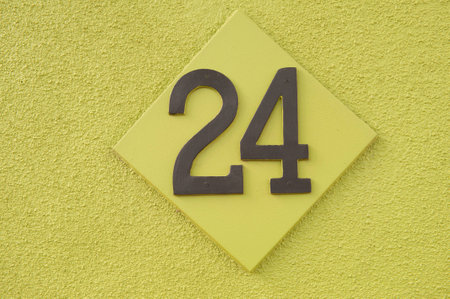 The Number 24 attached to the wall of a green textured buildingの写真素材
