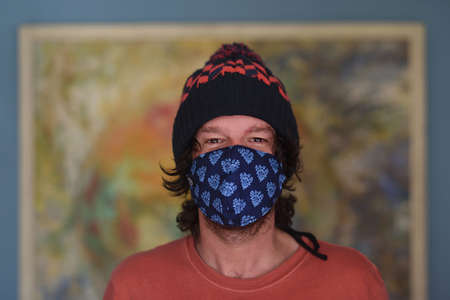Friendly portrait of creative man in the room with custom face mask.の写真素材
