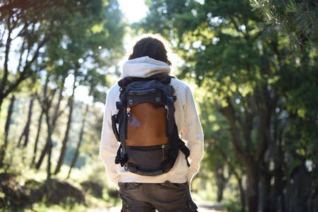 Man on his back with travel backpack at sunrise in the forest.の写真素材