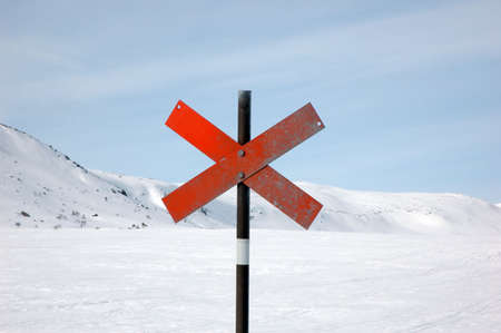 Red trail markers in the form of a cross against a snowy background.の写真素材