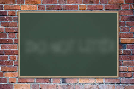A blank blackboard against a brick wall.の写真素材